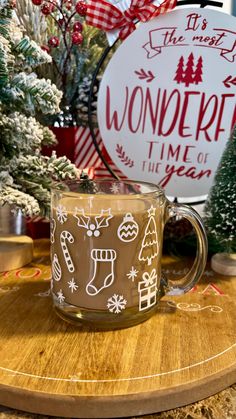 a coffee mug sitting on top of a wooden table next to christmas trees and other decorations