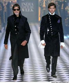 two men walking down the runway in black outfits