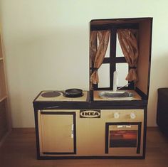 an old fashioned kitchen playset in the corner of a room with a couch and window