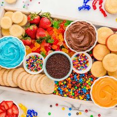 a box filled with lots of different types of food next to cupcakes and strawberries