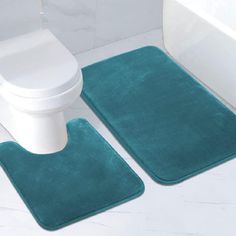 two bathroom rugs on the floor next to a toilet