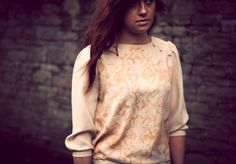 a woman standing in front of a brick wall with her hair blowing in the wind