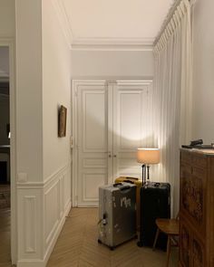 two pieces of luggage sitting on the floor in front of a lamp next to a dresser