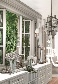 a room filled with lots of white furniture and green plants on the windows sill