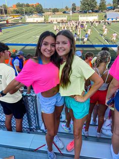 two girls are standing on the bleachers with their arms around each other