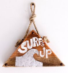 a wooden sign that says surf's up hanging from a rope on a wall