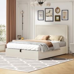 a white bed sitting on top of a hard wood floor next to a large window