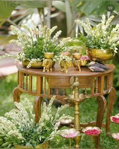 a table with flowers and plants on it in the middle of some grass, surrounded by other plant life