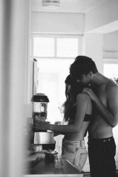 a man and woman standing next to each other in a kitchen with blenders on the counter