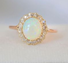 an opal and diamond ring on a white surface