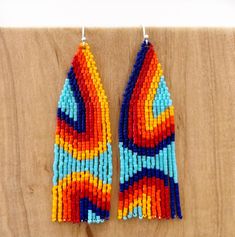 two pairs of beaded earrings on a wooden surface