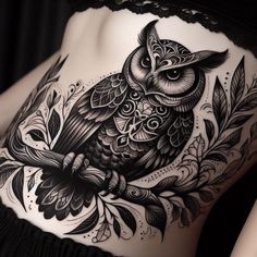 an owl tattoo on the back of a woman's stomach, with leaves and flowers