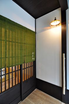 an empty room with green blinds on the wall and wood flooring in front of it