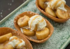 bananas and ice cream in small bowls on a green tray with water droplets around them