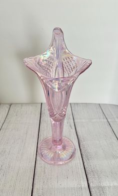 a pink glass vase sitting on top of a wooden table