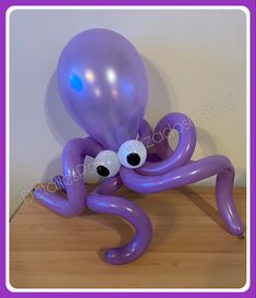 an octopus balloon sitting on top of a wooden table next to a purple ballon