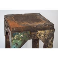 an old wooden stool with rusted paint on the top and bottom, sitting against a white wall