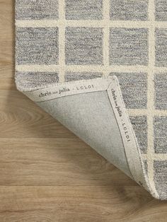 a close up view of a rug on a wooden floor with a white and gray checkerboard pattern