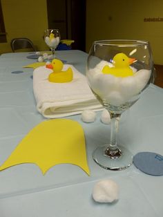 a table topped with a glass filled with water and rubber ducks