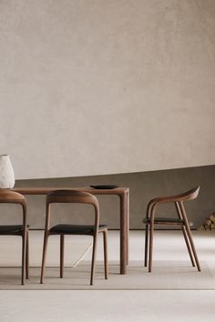 three chairs and a table in front of a wall