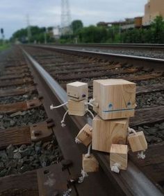 a wooden robot sitting on top of train tracks