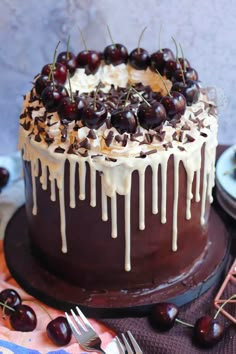 a chocolate cake topped with cherries and drizzled in icing