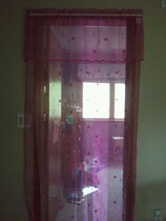 the window is covered with pink sheer curtains