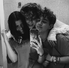 three young women hugging each other and taking a selfie with their cell phone in the bathroom