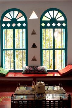 a room with two large windows and a coffee table in front of it on the floor