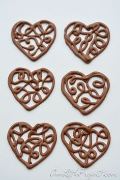 four heart shaped cookies with swirly chocolate icing