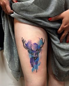 a woman's thigh with a watercolor deer head tattoo on her left leg