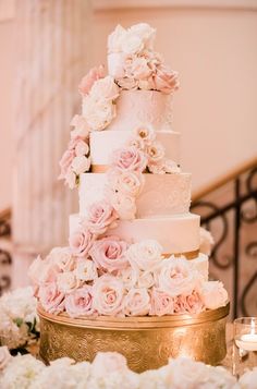 a wedding cake with pink and white flowers on the top is sitting on a table