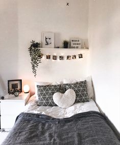 a bed with two pillows and some pictures on the wall above it in a bedroom