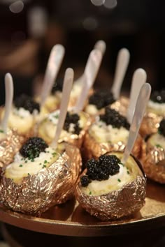 small desserts with spoons sticking out of them on a gold platter at a party