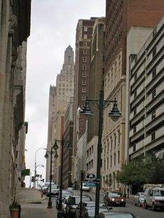 a city street with cars parked on both sides and tall buildings in the back ground