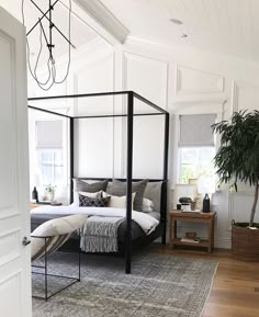 a bedroom with a four poster bed, rug and potted plant in the corner