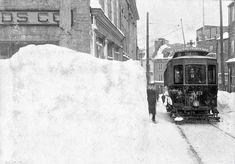 an old photo of a man standing in the snow next to a train on tracks