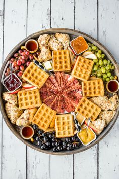 a platter filled with waffles, grapes and other foods