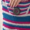 the woman is wearing a striped sweater with buttons on her belt and has her hands in her pocket