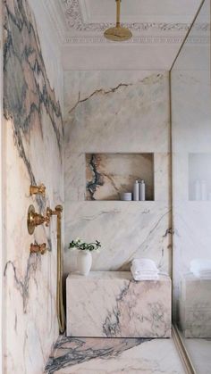 a bathroom with marble walls and flooring in white, gold and black colors is shown