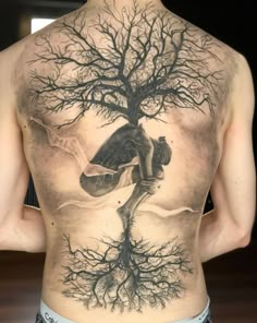 a man's back with a tree tattoo on his body and the image of a skateboarder