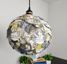 a lamp hanging from a ceiling in a room with books on the table and a plant