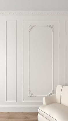 a white couch sitting in front of a wall with an ornate frame on it's side