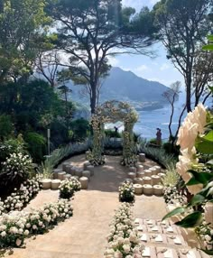 an outdoor ceremony setup with flowers and greenery on the ground, overlooking the water