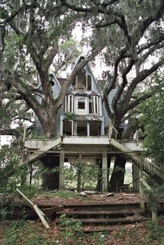 an old house in the woods with stairs leading up to it's second story