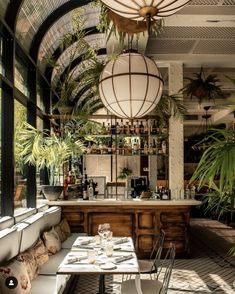 a restaurant with tables, chairs and plants hanging from the ceiling in front of it