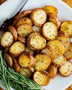 a white plate topped with sliced potatoes and rosemary garnish next to a fork