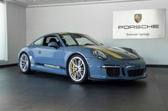 a blue porsche sports car in a showroom with the porsche logo on the wall