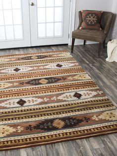 a brown chair sitting on top of a wooden floor next to a rug and door