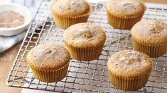 several muffins on a cooling rack with some powdered sugar in the background